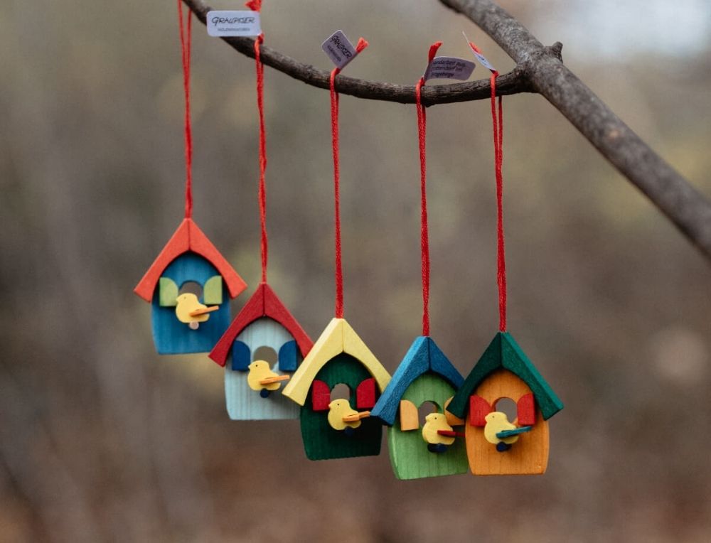 Colourful Graupner birdhouse ornaments hanging from a branch