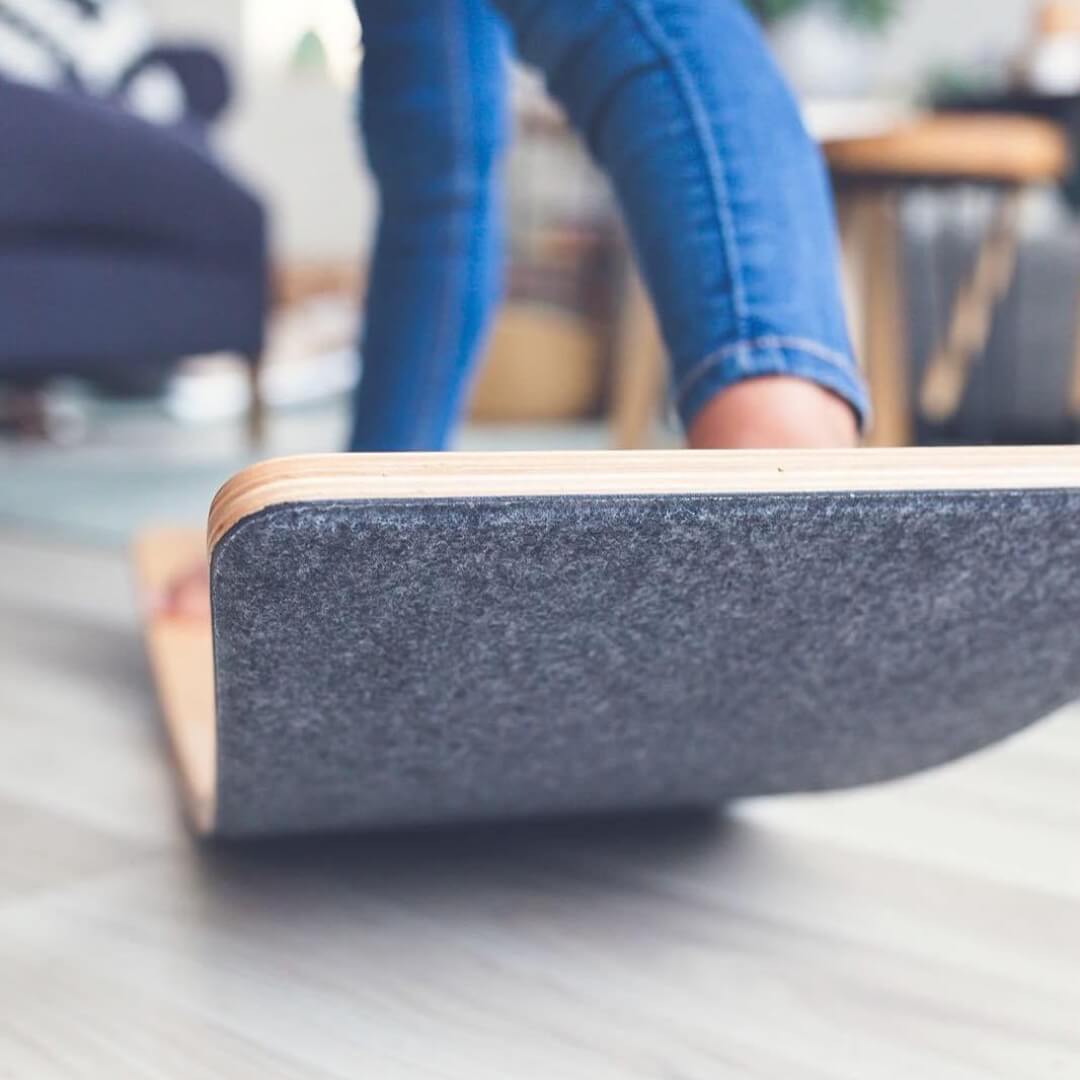Child rocking on Wobbel Board featuring an all-natural wool felt base, from Wooden Playroom in Australia