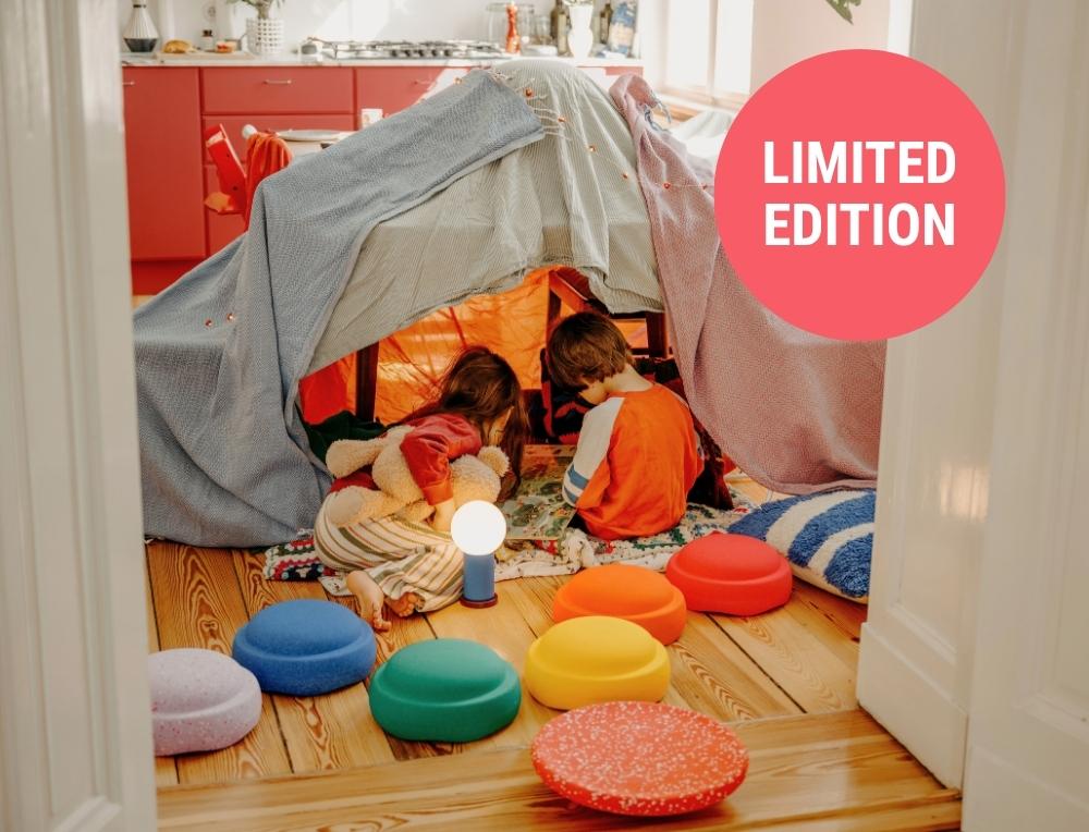 Children reading together in a living room blanket den with Limited Edition Hidden Giants Stapelstein stepping stones in the foreground
