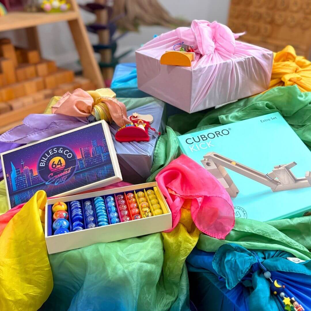 Children's Christmas gifts wrapped in colourful Sarah's Silks with opened Billes and Co marbles and CUBORO marble run set 