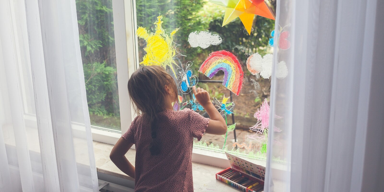 Child drawing on the window with water soluble Kitpas art crayons at Wooden Playroom in Australia