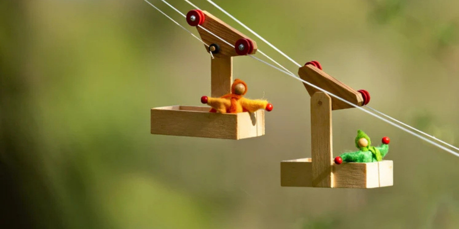 Kraul Toy wooden cable car with two small figures on a blurred green background