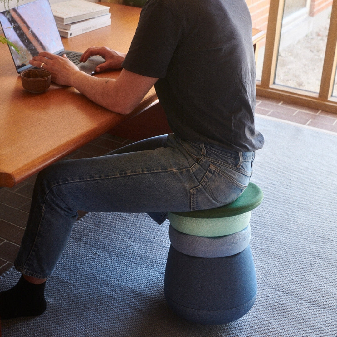Person sitting on Stapelstein Dynamic stool at a desk using a laptop.