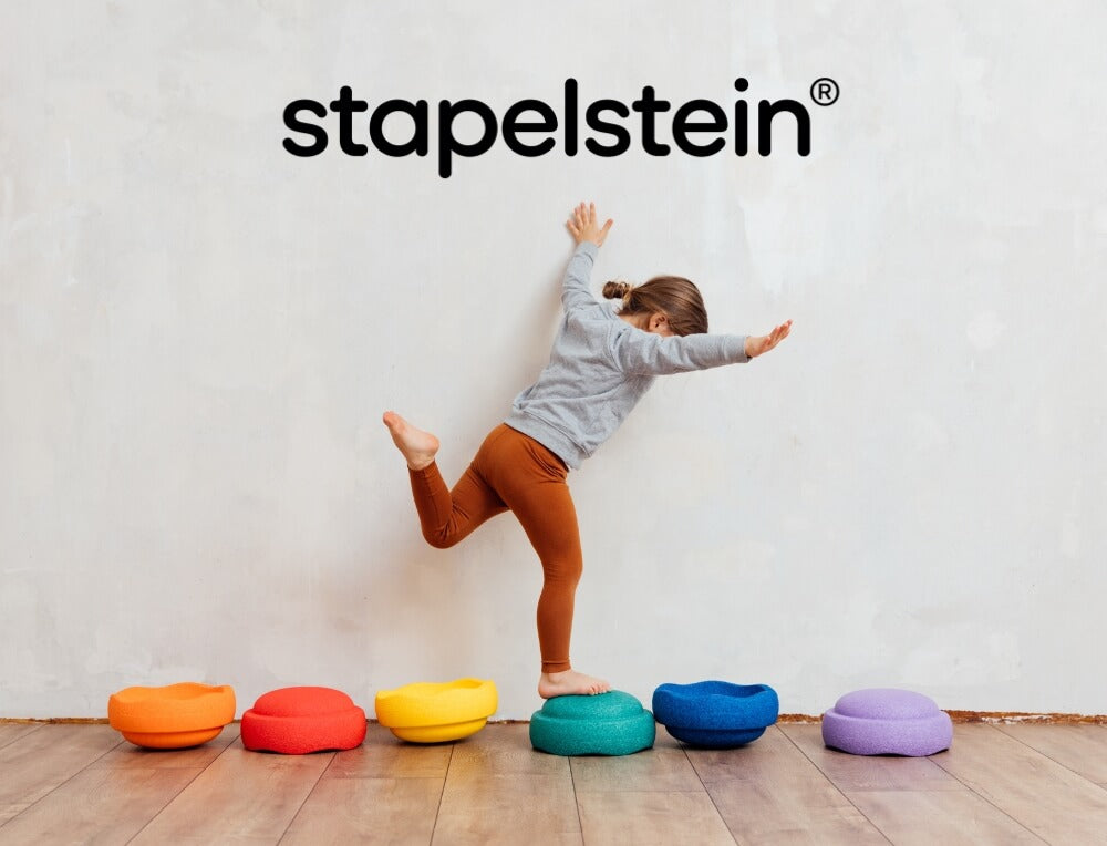 Child balancing on Stapelstein stepping stones with 'stapelstein' logo above