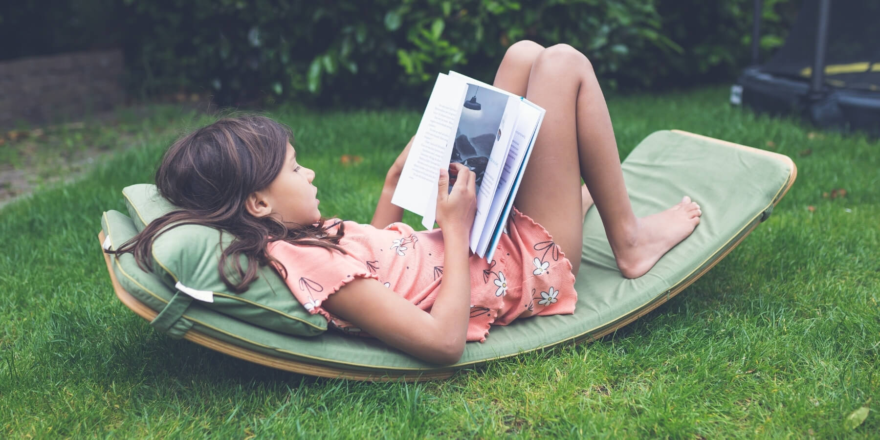 Child relaxing on a Wobbel Board with comfortable deck and pillow while reading a book - Wooden Playroom Australia