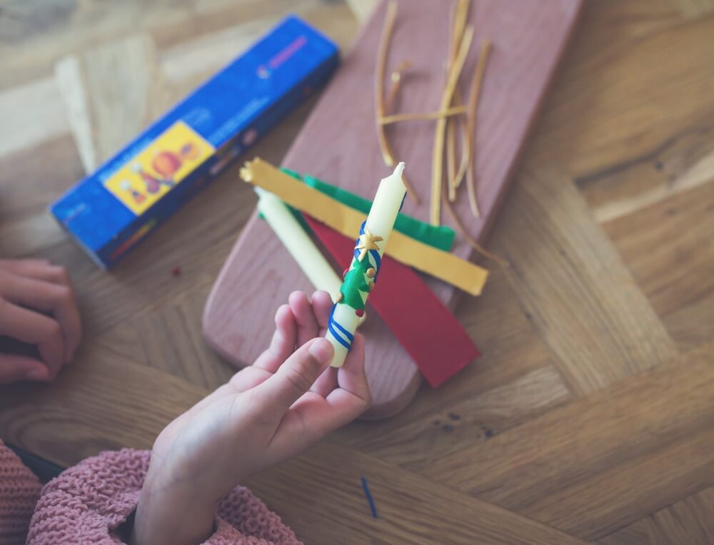 Child's hand holding a Christmas candle decorated with Stockmar modelling wax