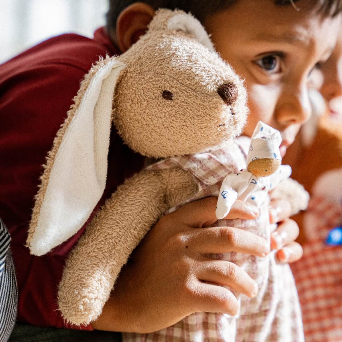 Child cuddling with Kathe Kruse cuddly rabbit toy from Wooden Playroom in Australia